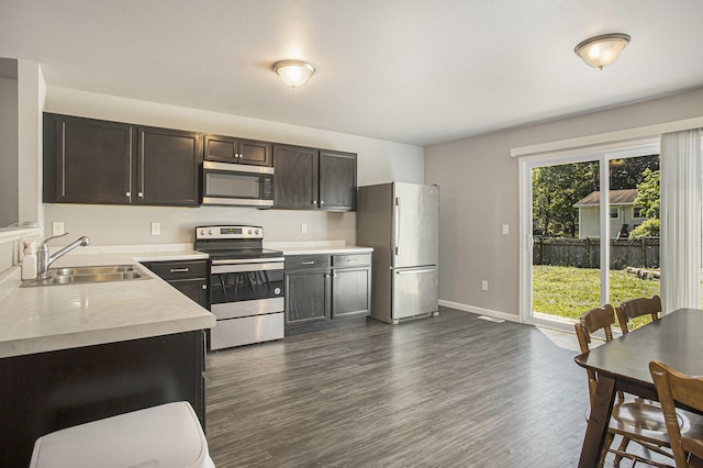 kitchen featuring stainless steel appliances, a sink, light countertops, dark wood-style flooring, and dark brown cabinets