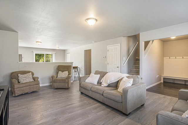 living room with wood finished floors, baseboards, and stairway