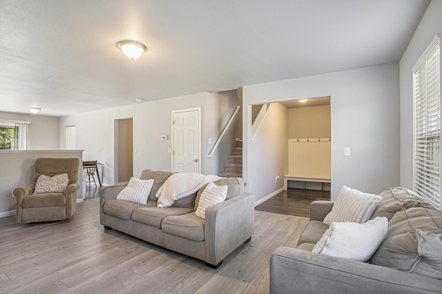 living area with wood finished floors, baseboards, and stairs