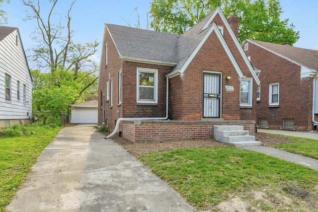 13575 Rutherford St, Detroit, MI 48227 - tudor house with a chimney, a shingled roof, brick siding, a detached garage, and an outdoor structure
