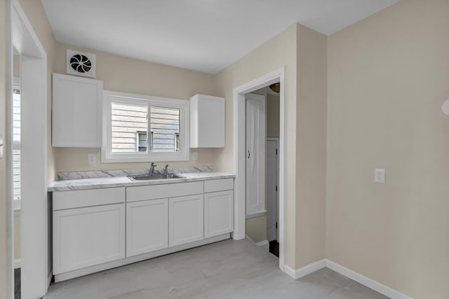 13575 Rutherford St, Detroit, MI 48227 - kitchen featuring a sink, light countertops, baseboards, and white cabinets