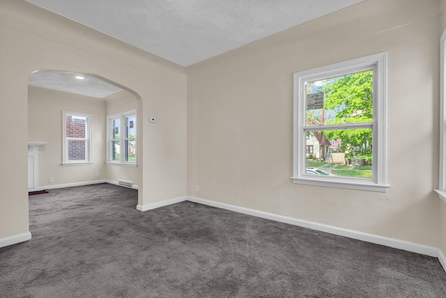 13575 Rutherford St, Detroit, MI 48227 - empty room with arched walkways, dark carpet, and baseboards