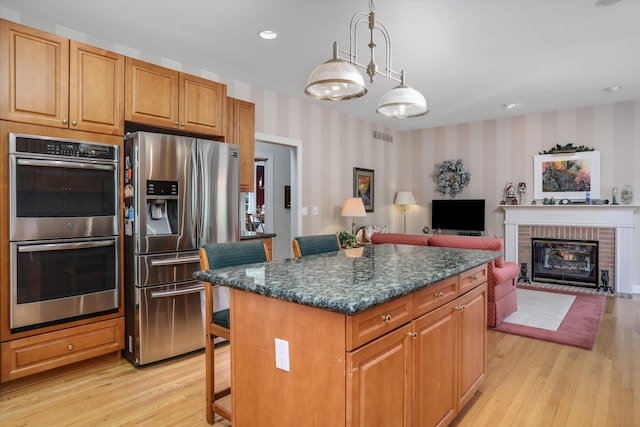30465 Stonegate Dr, Franklin, MI 48025 - kitchen featuring wallpapered walls, appliances with stainless steel finishes, light wood-type flooring, a center island, and open floor plan