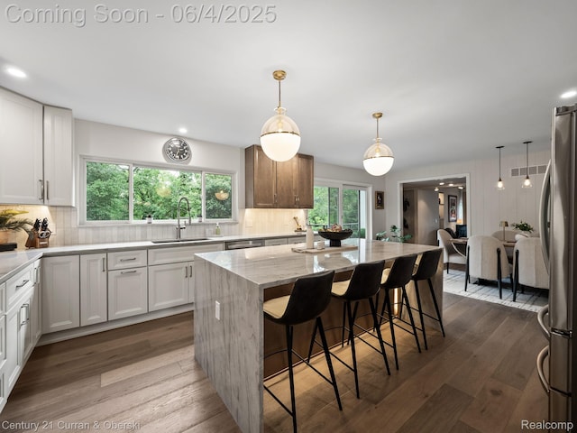 1985 Lone Pine Rd, Bloomfield Hills, MI 48302 - kitchen with a sink, stainless steel appliances, dark wood finished floors, light stone counters, and a kitchen island