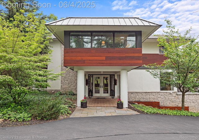 1985 Lone Pine Rd, Bloomfield Hills, MI 48302 - property entrance featuring french doors, a standing seam roof, stucco siding, and stone siding