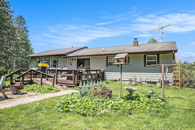 back of house featuring a deck, a chimney, and a yard