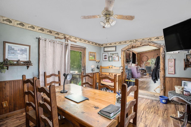 dining area with wainscoting, ceiling fan, wood finished floors, and wooden walls