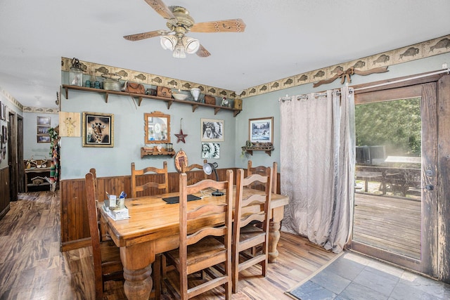 dining space featuring ceiling fan, wainscoting, and wood walls