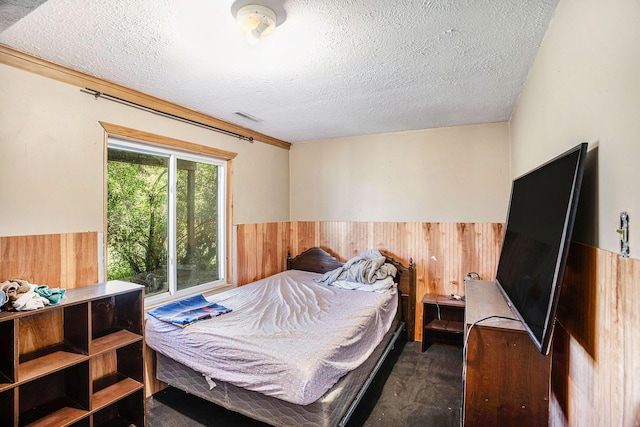 carpeted bedroom with wooden walls, a textured ceiling, and a wainscoted wall
