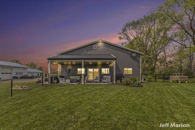 1525 W David Hwy, Ionia, MI 48846 - back of property at dusk with an outdoor living space, board and batten siding, a patio, ceiling fan, and a garage