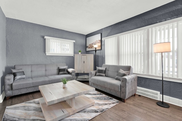 living room featuring a textured wall, wood finished floors, and baseboards
