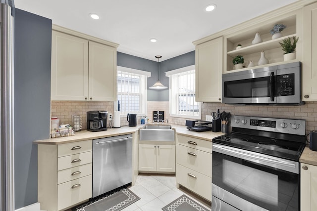 kitchen featuring stainless steel appliances, a sink, light countertops, backsplash, and recessed lighting