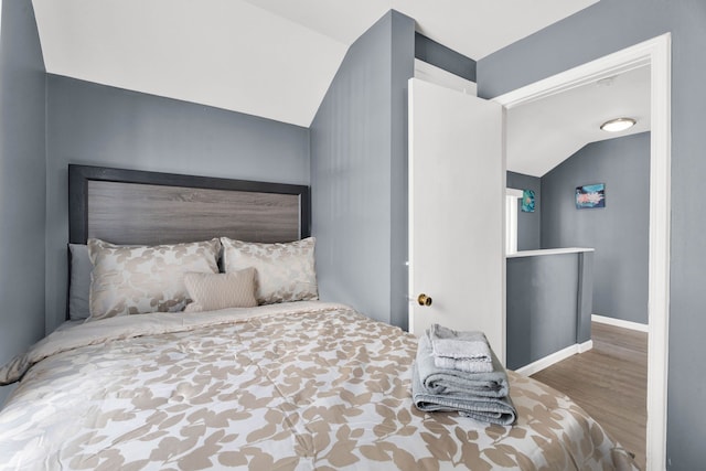 bedroom featuring lofted ceiling, wood finished floors, and baseboards