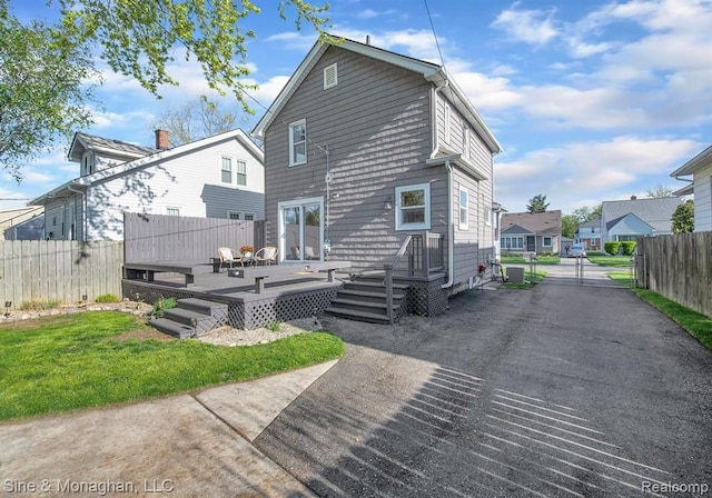 back of property with a deck and a gate