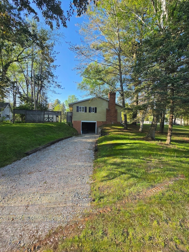 7400 Willow, Lexington, MI 48450 - split level home featuring an attached garage, dirt driveway, a chimney, and a front yard