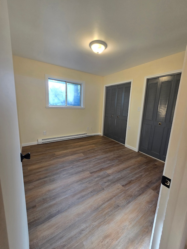 7400 Willow, Lexington, MI 48450 - unfurnished bedroom featuring a baseboard heating unit, multiple closets, dark wood-type flooring, and baseboards