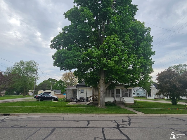 view of property hidden behind natural elements featuring a front lawn