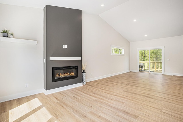 370 Chopin Dr, Muskegon, MI 49442 - unfurnished living room featuring high vaulted ceiling, light wood-type flooring, a glass covered fireplace, recessed lighting, and baseboards