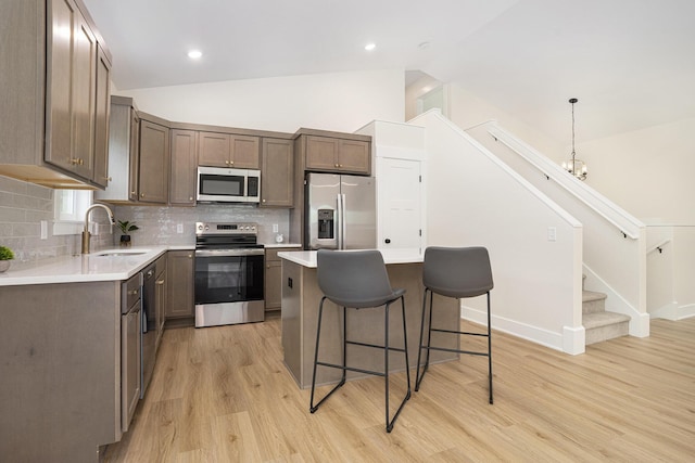 370 Chopin Dr, Muskegon, MI 49442 - kitchen featuring appliances with stainless steel finishes, a sink, lofted ceiling, a kitchen breakfast bar, and light wood-style flooring