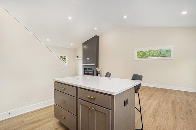 370 Chopin Dr, Muskegon, MI 49442 - kitchen featuring a kitchen bar, a kitchen island, light wood-type flooring, vaulted ceiling, and light countertops