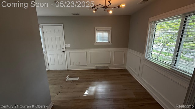 648 W Hazelhurst St, Ferndale, MI 48220 - unfurnished dining area with healthy amount of natural light, a chandelier, wainscoting, dark wood-style floors, and a decorative wall