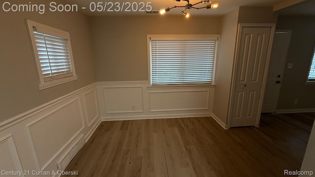 648 W Hazelhurst St, Ferndale, MI 48220 - unfurnished room featuring a chandelier, a decorative wall, wood finished floors, plenty of natural light, and wainscoting