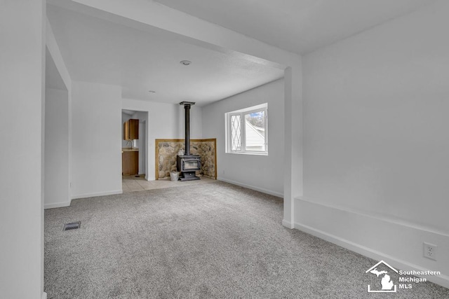7316 Summerfield Rd, Lambertville, MI 48144 - unfurnished living room with a wood stove, carpet floors, and baseboards