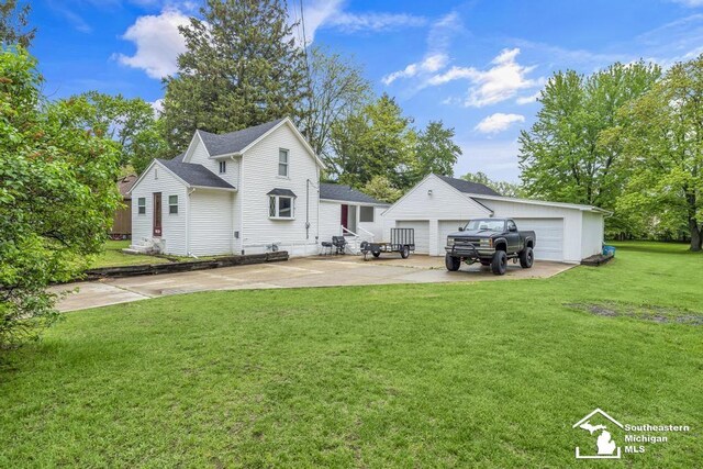 7316 Summerfield Rd, Lambertville, MI 48144 - rear view of house featuring a detached garage, an outbuilding, a lawn, a patio, and a shingled roof