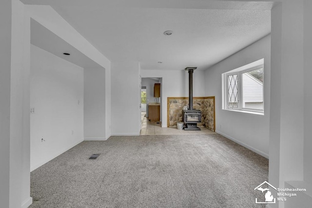 7316 Summerfield Rd, Lambertville, MI 48144 - unfurnished living room featuring carpet flooring, a wood stove, and baseboards