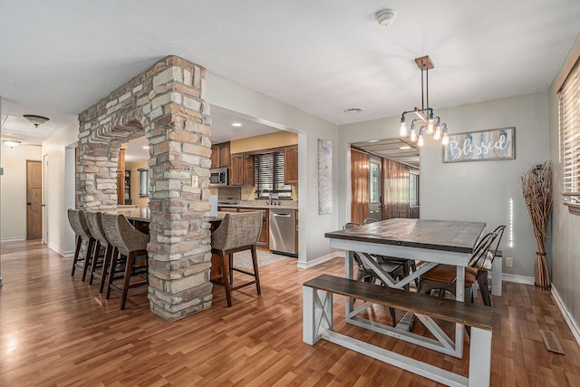 1514 Ferndale Blvd, Niles, MI 49120 - dining room with decorative columns, light wood-style floors, baseboards, and a chandelier
