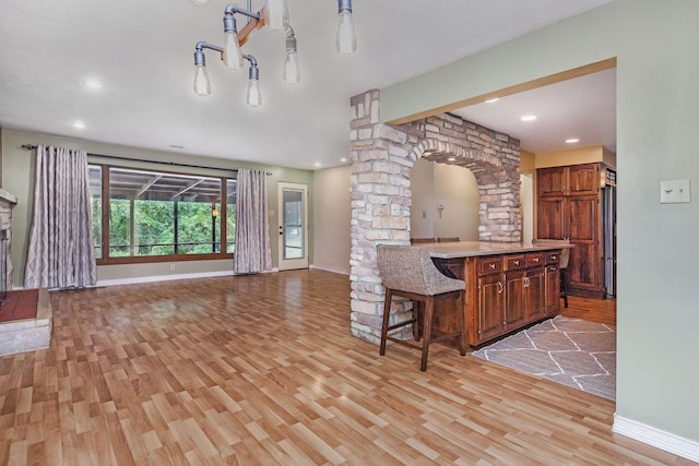 1514 Ferndale Blvd, Niles, MI 49120 - kitchen featuring light wood finished floors, open floor plan, a breakfast bar, baseboards, and ornate columns