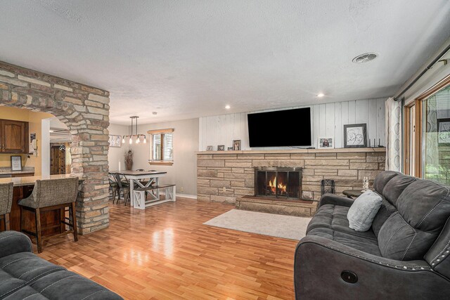 1514 Ferndale Blvd, Niles, MI 49120 - living area featuring ornate columns, light wood-type flooring, baseboards, a textured ceiling, and a fireplace