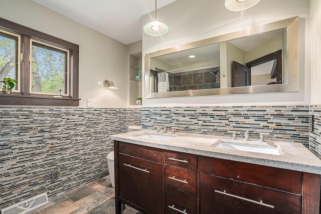1514 Ferndale Blvd, Niles, MI 49120 - bathroom featuring tile walls, toilet, double vanity, stone finish floors, and decorative backsplash