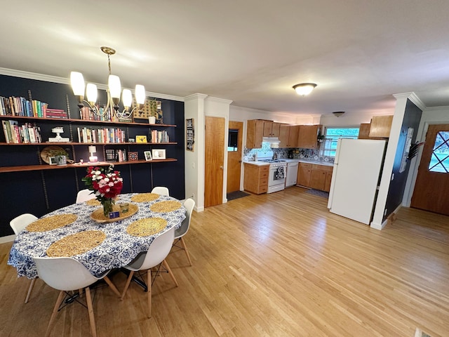 dining area featuring light wood-type flooring, a chandelier, crown molding, and baseboards