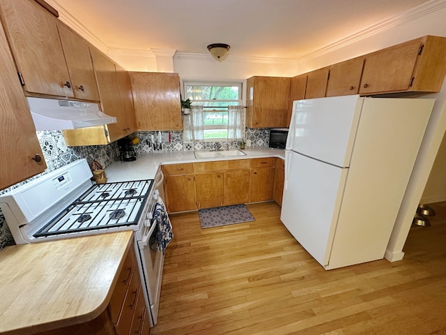 kitchen with white appliances, under cabinet range hood, a sink, light wood-style flooring, and light countertops