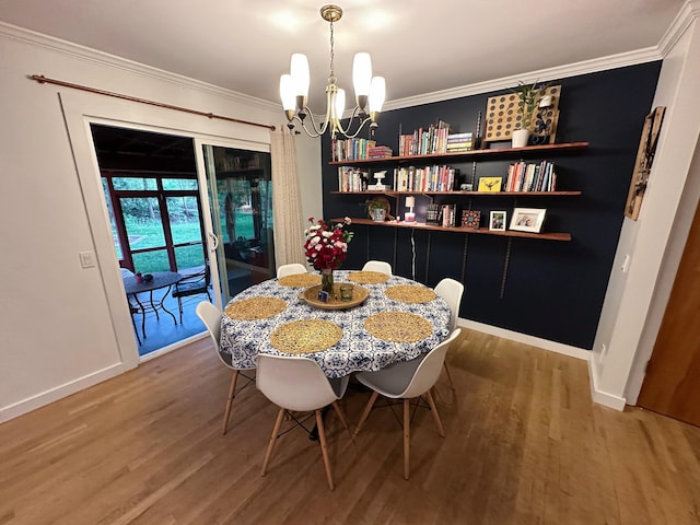 dining space featuring wood finished floors, a chandelier, ornamental molding, and baseboards