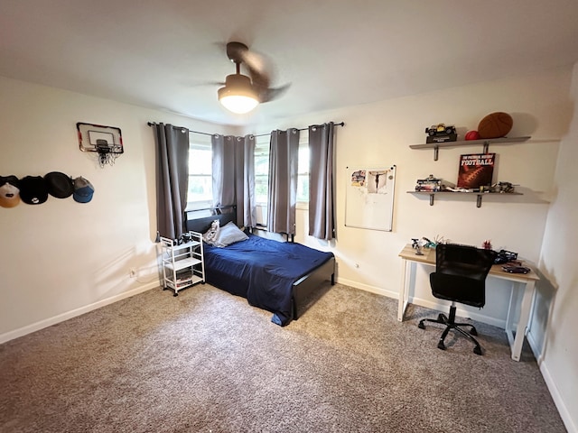 carpeted bedroom featuring an office area, baseboards, and a ceiling fan