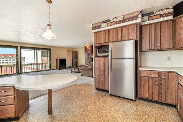 929 S Washington Ave, Ludington, MI 49431 - kitchen with stainless steel appliances, a textured ceiling, brown cabinetry, light countertops, and decorative light fixtures