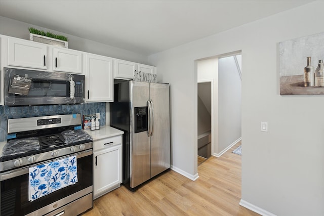 kitchen with appliances with stainless steel finishes, white cabinetry, and light wood-style floors