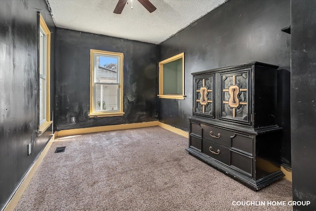 unfurnished bedroom featuring carpet floors, a textured ceiling, baseboards, and a ceiling fan