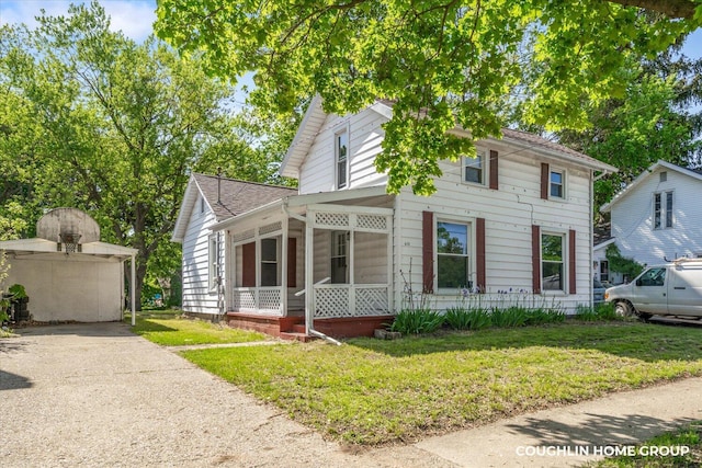 view of front of house with a sunroom, a front lawn, and a shingled roof