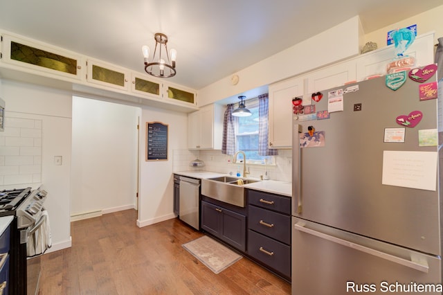 1572 Cornell Rd, Muskegon, MI 49441 - kitchen with stainless steel appliances, white cabinetry, a chandelier, light countertops, and backsplash