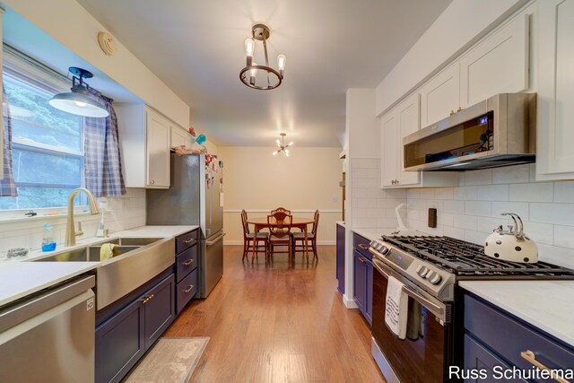 1572 Cornell Rd, Muskegon, MI 49441 - kitchen featuring stainless steel appliances, white cabinets, light countertops, backsplash, and light wood-style floors