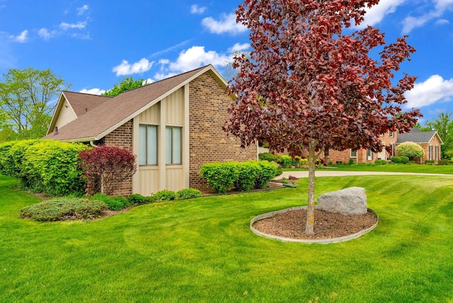 836 Boutell Dr, Grand Blanc, MI 48439 - view of home's exterior with brick siding, board and batten siding, a yard, and roof with shingles