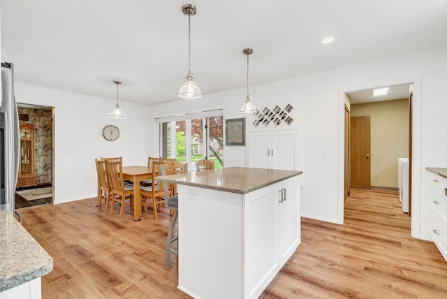 836 Boutell Dr, Grand Blanc, MI 48439 - kitchen featuring light wood-style flooring, white cabinets, light stone countertops, a center island, and hanging light fixtures
