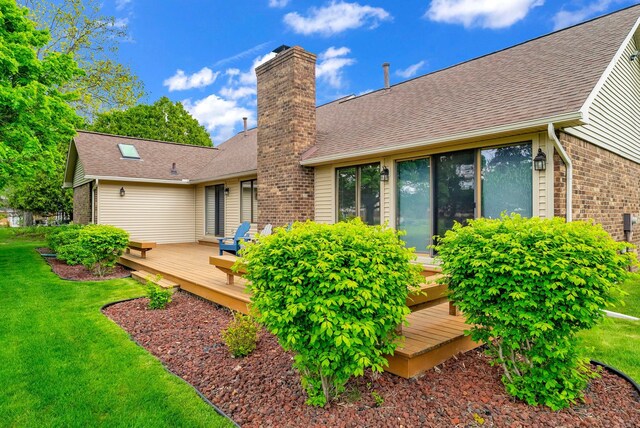 836 Boutell Dr, Grand Blanc, MI 48439 - back of house with a chimney, a wooden deck, brick siding, and a lawn