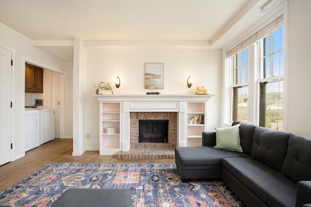 living room with independent washer and dryer, light wood-type flooring, a fireplace, and baseboards