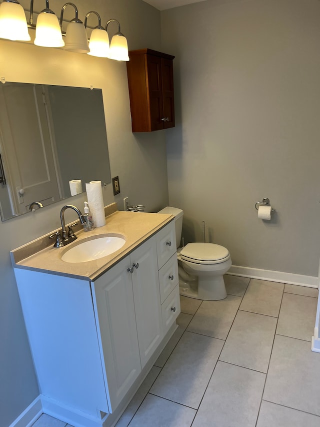 bathroom with toilet, vanity, tile patterned flooring, and baseboards