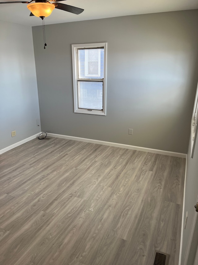 spare room featuring ceiling fan, wood finished floors, and baseboards