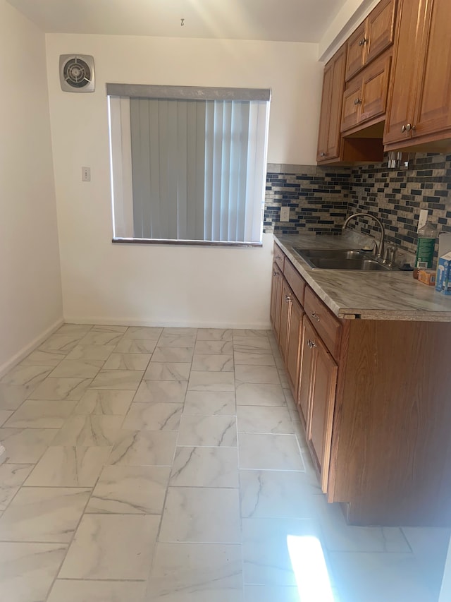 19121 Curtis St, Detroit, MI 48219 - kitchen with a sink, light marble finish floors, baseboards, and brown cabinetry